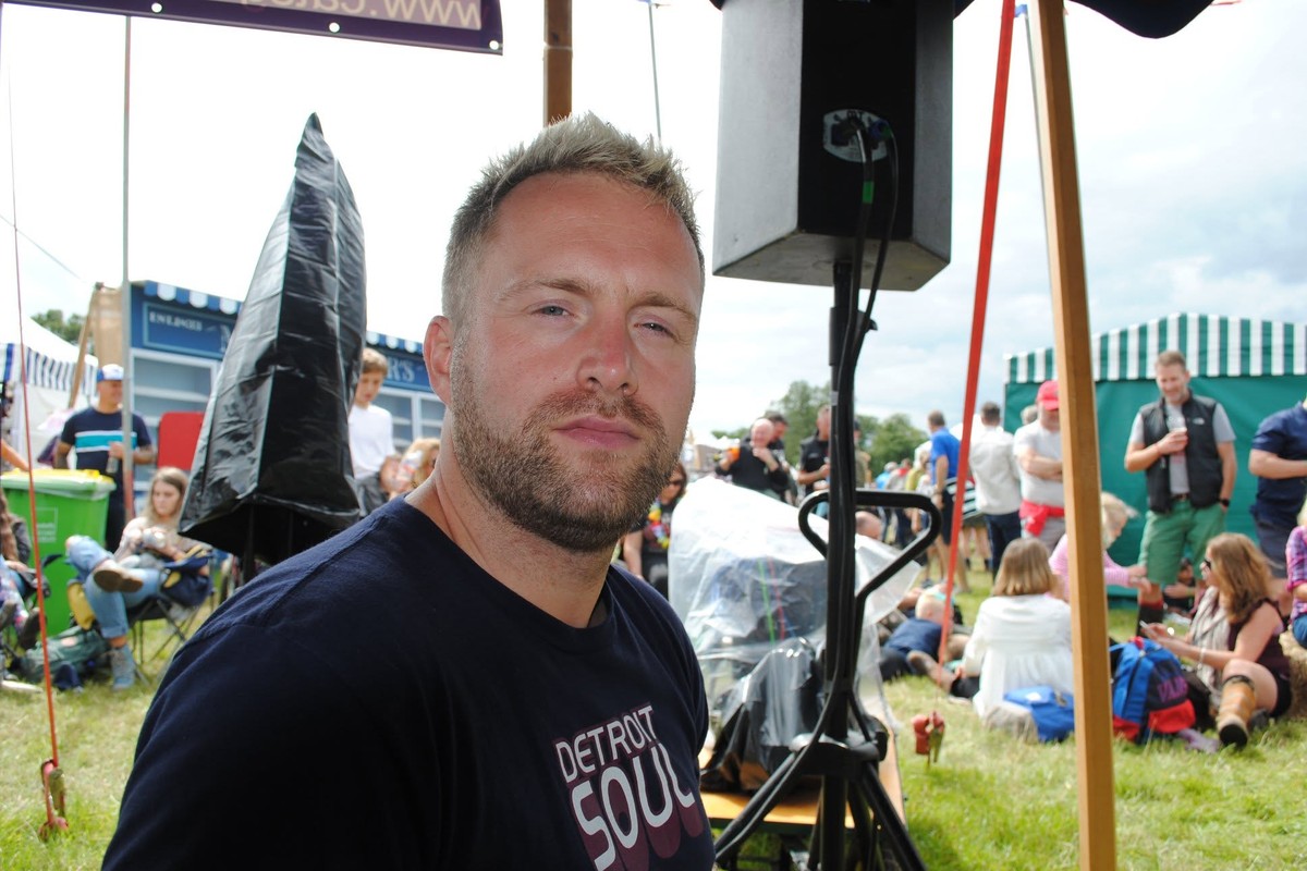 Dan Johnson at an outdoor market festival, with stalls and crowds behind him